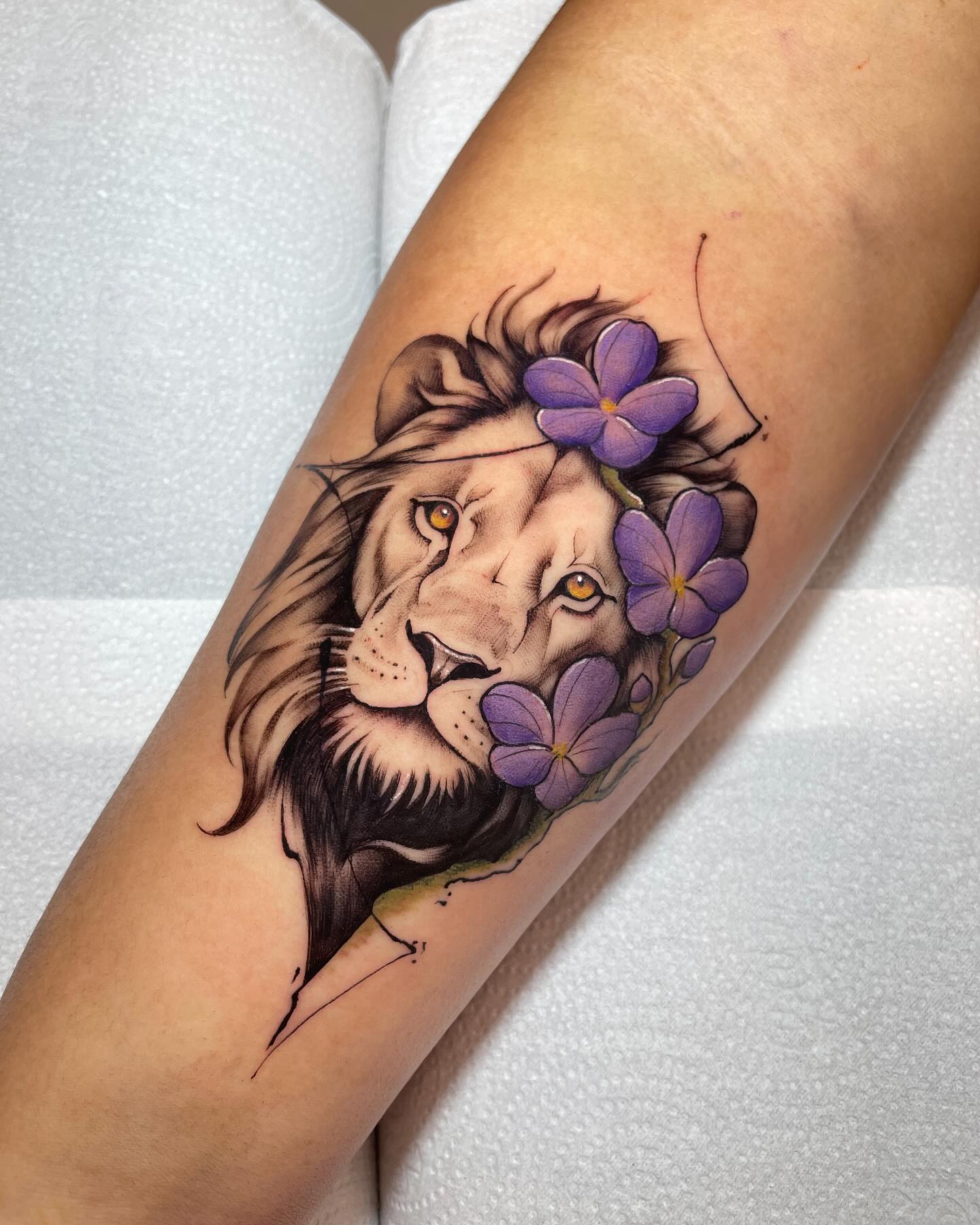 Tatuagem realista colorida de leão com flores
